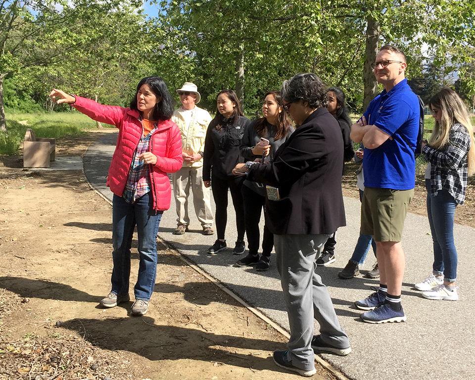 image of students on an outdoor trailing looking towards a place someone is pointing to out of frame.