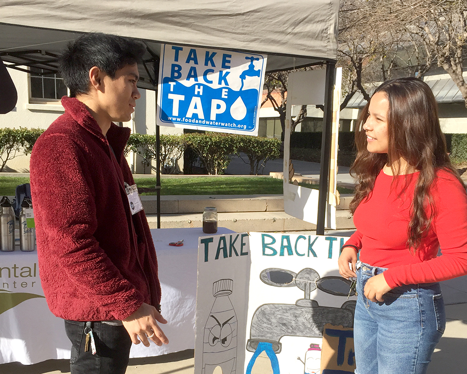 two students talking in front of a tabling tent